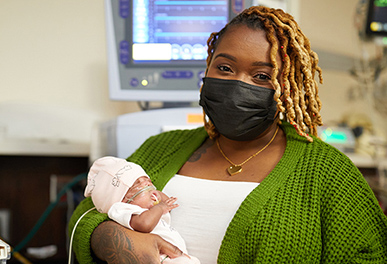 Mother holding newborn in UMC hospital room